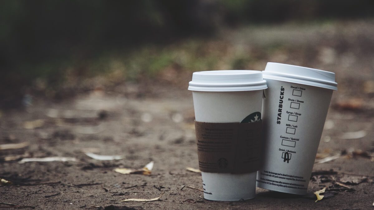 two starbucks coffees sitting in the fall leaves