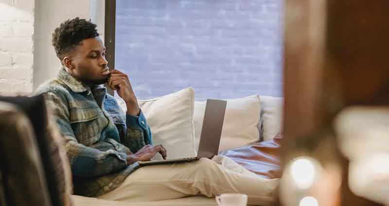 man on laptop sitting on couch concentrated