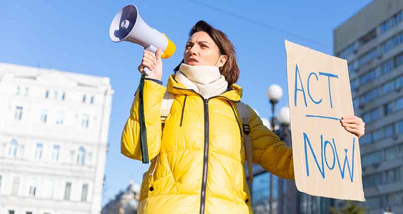 woman holding megaphone and a sign that says act now
