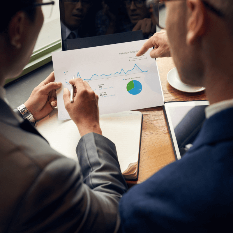 two businessmen studying impact of blogging through trend chart and pie chart