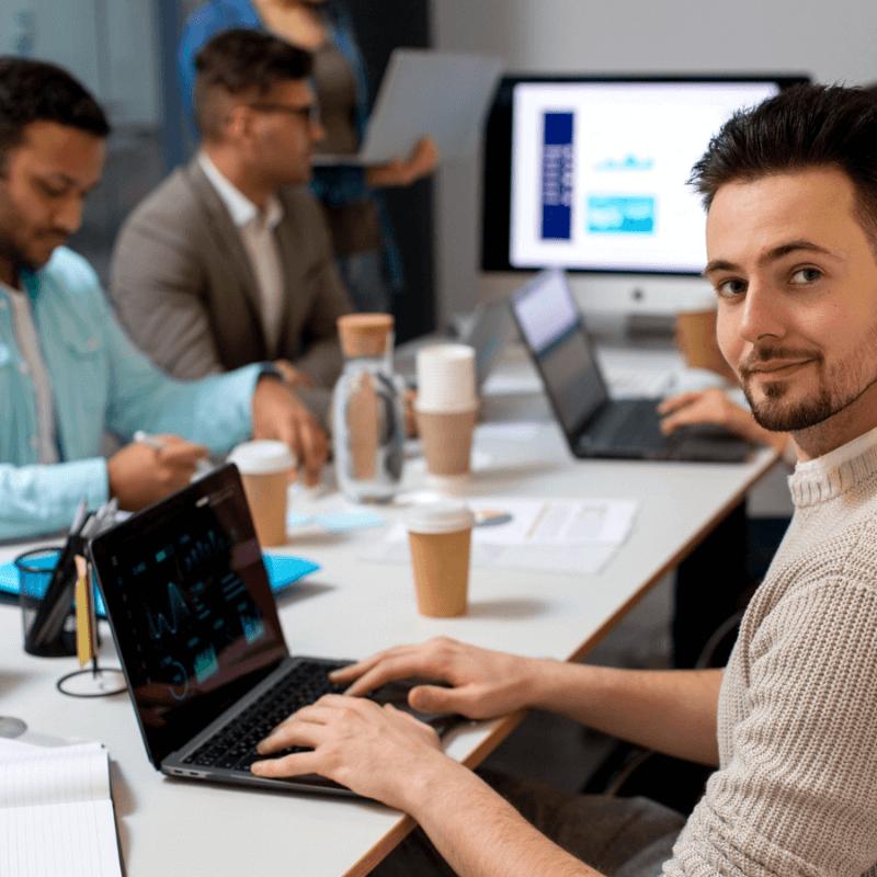 web dev agency meeting room, developer looking at camera smiling