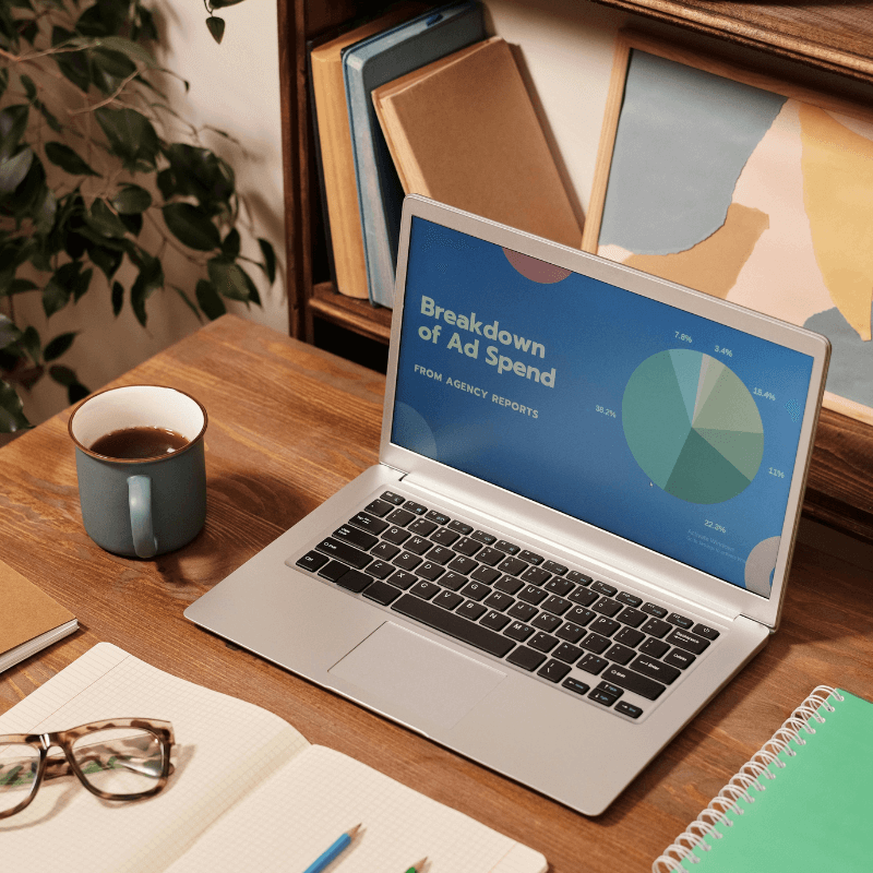 laptop on desk, showing breakdown of ad spend from agency reports